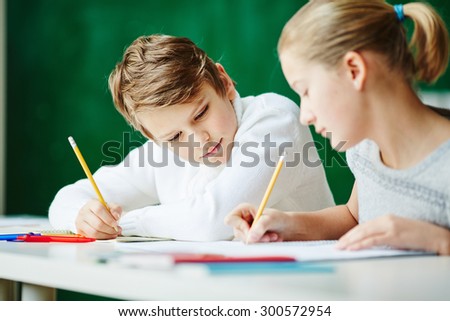 Youthful schoolkids drawing together at lesson