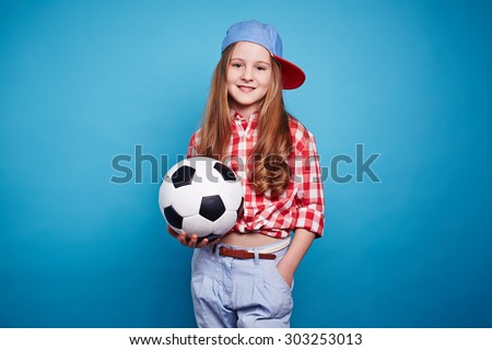 Smiling girl holding soccer ball and looking at camera