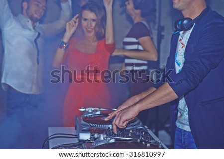 Male deejay adjusting sound on background of dancing friends