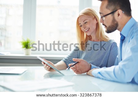 Two colleagues looking at data in touchpad while businessman giving explanations