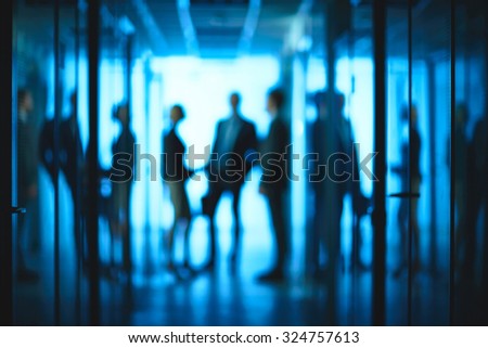 Silhouettes of co-workers interacting in corridor of office center