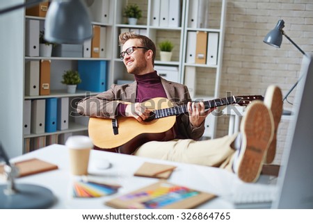 Handsome businessman playing the guitar in office after work