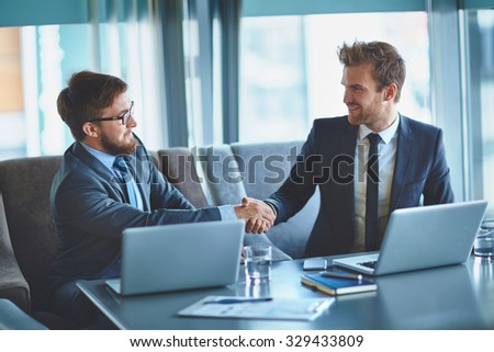 Young businessmen handshaking in office after making agreement