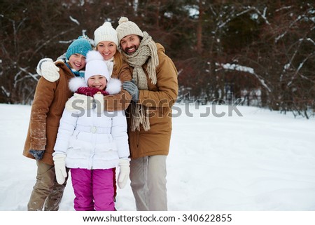 Happy family of four looking at camera in winter park