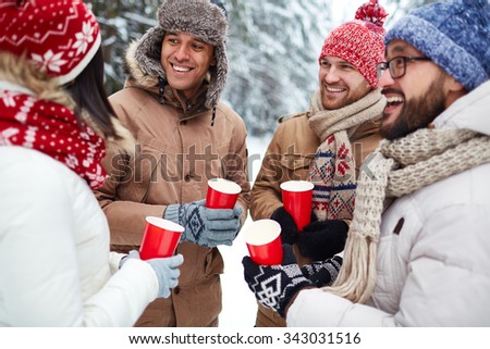 Group of friends with hot drinks spending leisure in winter environment