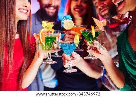 Cheerful friends holding martini glasses with cocktails