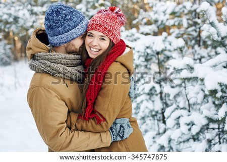 Young embracing couple looking at camera in park
