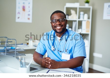 Smiling doctor sitting at the table in his office