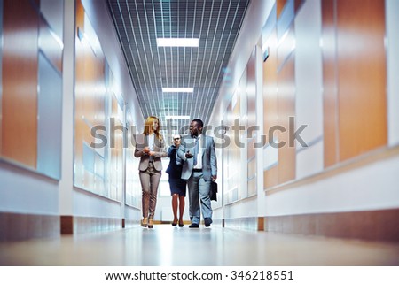 Business people walking down the office corridor and communicating