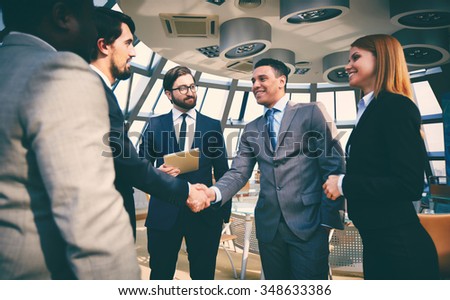 Business partners greeting one another by handshaking