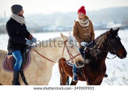 Smiling couple riding on horses outdoors in winter