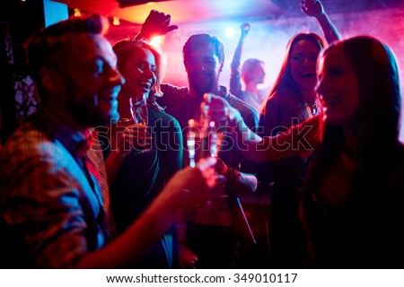 Group of young people celebrating with drinks in nightclub