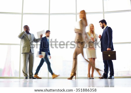 Blurred motion of several people working at office