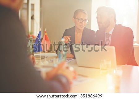 Young woman interpreting speech of partner to businessman at international conference
