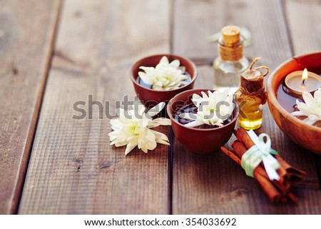 Bowls with flowers, bunch of cinnamon and aromatic oils in spa salon