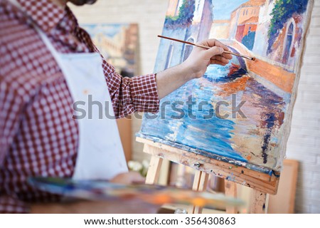 Hand of artist painting Italian landscape