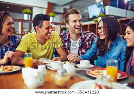 Happy teens talking during lunch in cafe