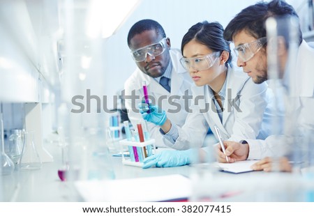 Group of young scientists studying new substances in flasks