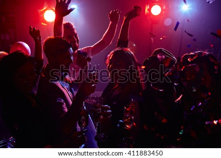 Joyful friends with champagne dancing in disco club