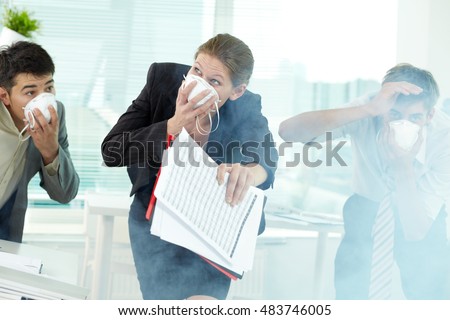 Three business people in gas masks gasping in office