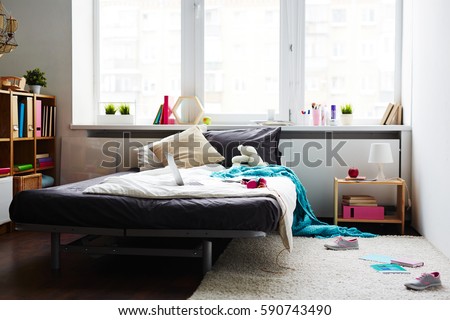 Modern messy girl bedroom with large bed, laptop, teddy bear and scattered sneakers on white soft carpet
