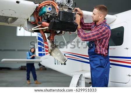 Airplane service team repairing plane in hangar:  modern mechanic fixing disassembled airplane turbine