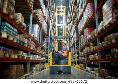 Worker in forklift-truck loading packed goods