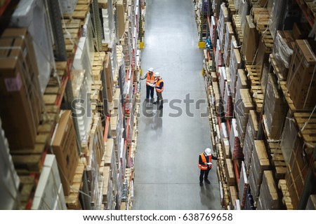 Group of workers in aisle between shelves with packed goods