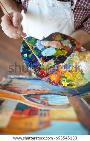 High angle shot of talented artist mixing colors on palette while painting picture in art studio