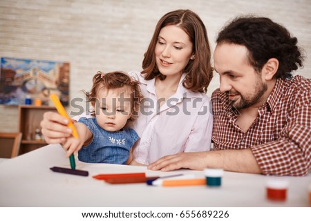 Portrait of happy family with little child drawing together in art class using crayons