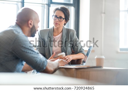 Serious woman listening to co-worker explaining new online business trends