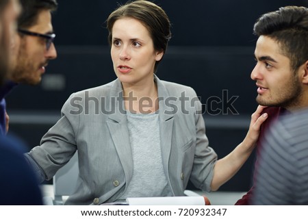 Experienced psychologist putting her hands on shoulders of two rivals during session