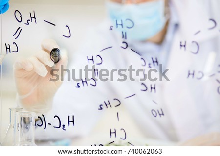 Chemist writing with highlighter formula of molecular structure on transparent board
