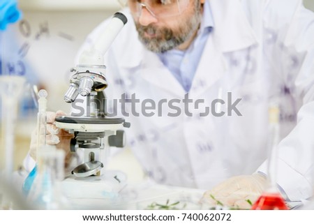 Modern researcher studying chemical elements or substances in microscope