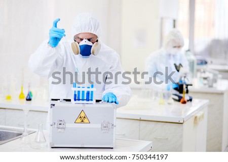 Scientist dropping liquid substance into flask with toxic fluid
