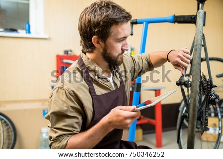 Repair specialist with tablet searching in the net about fixing wheel of bike