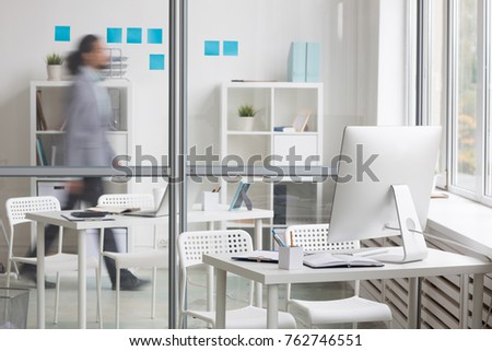 Business workplace by transparent wall and moving businessman behind it