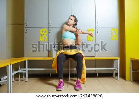 Young sportswoman in changing room warming up before training in gym