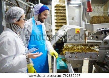 Two workers of seafood plant having talk by producing-line of seaweed salad