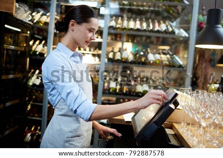 Young waitress or cashier registrating new orders of clients in computer