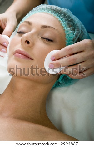 Pretty woman with closed eyes enjoys the face massage in the spa