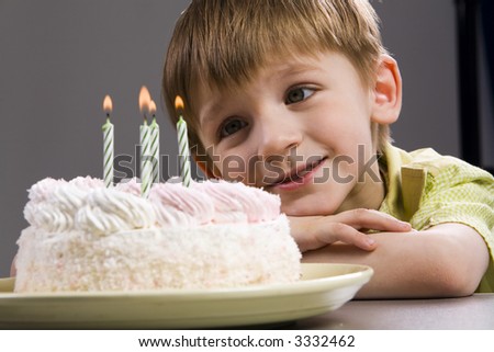 Happy blond boy with birthday cake looking at the candles
