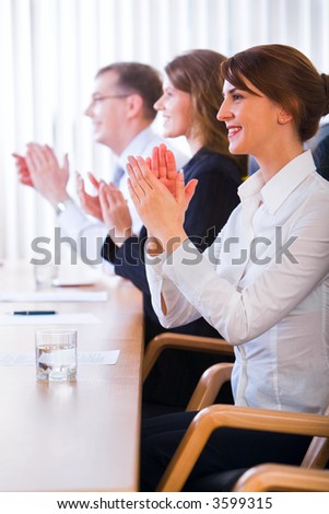 Successful applauding young people standing near by the table with black comfortable chairs