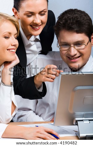 Business woman is explaining the correct way of analysis to his colleagues in  the office pointing at he monitor