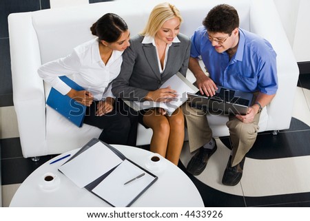 Portrait of three smiling business people sitting on the sofa and discussing an interesting idea