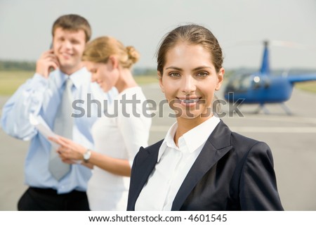 Portrait of confident young woman smiling on a background of two business people and the helicopter