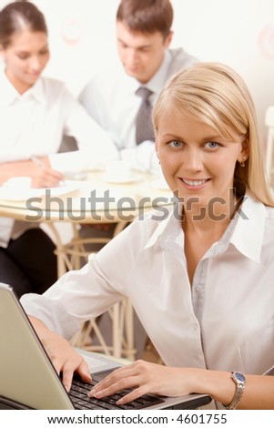 Young successful smiling woman is typing a text on her laptop in the cafe