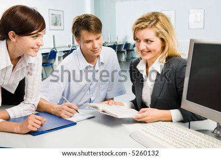 Group of three young business people are discussing new teaching material in the computer room