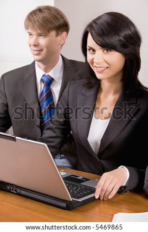 Responsible woman is smiling and sitting at the table near business man