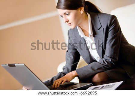 Portrait of pretty smiling woman sitting at the table with laptop and paperwork